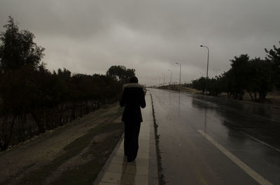 Man walking on road against sky
