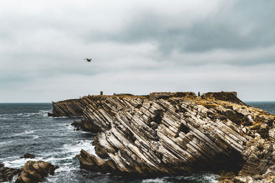 Scenic view of rocky coastline in sea against sky