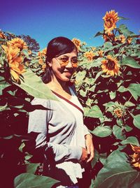 Portrait of smiling young woman by flowering plants during autumn