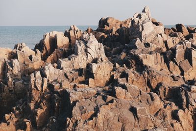 Rock formations by sea against clear sky