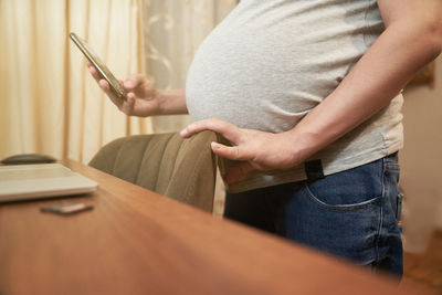 Midsection of pregnant woman using smartphone 
