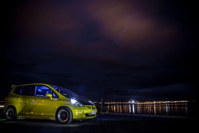 Car on illuminated road against sky at night