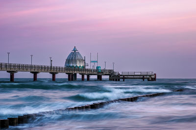 Bridge over sea against sky during sunset