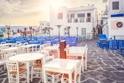 Empty chairs and tables at sidewalk cafe against buildings in city