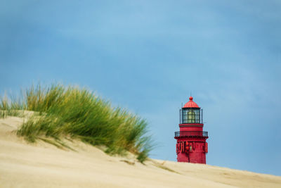 Lighthouse on beach against sky