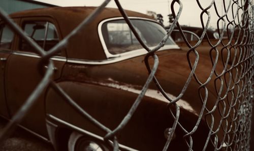 Vintage car seen through chainlink fence