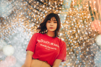 Portrait of young woman standing against christmas tree