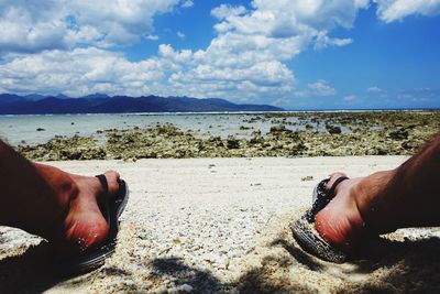 Low section of man on beach against sky