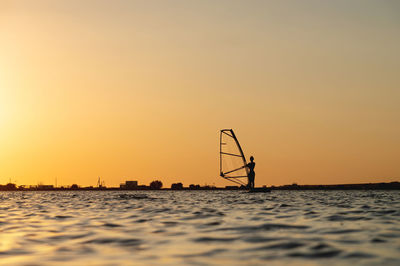 Woman windsurfer silhouette at lake sunset.beautiful beach landscape. summer water sports activities