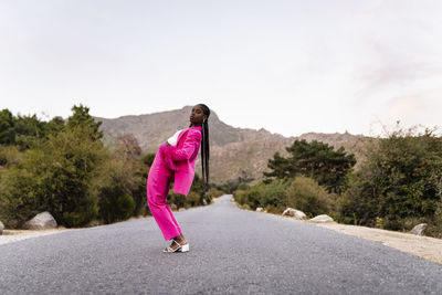 Young woman bending backwards standing on road
