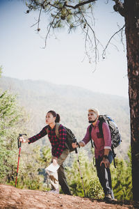 Man and woman hiking against sky