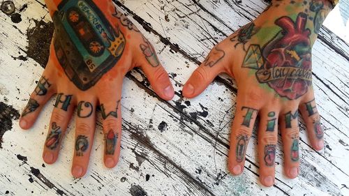 Close-up of hands with tattoo on table