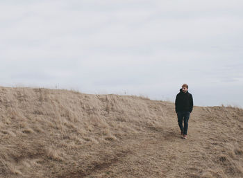 Rear view of man standing on beach against sky