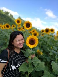 Close-up of young woman with sunflower standing against plants