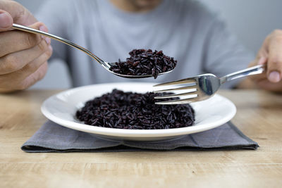 Midsection of person having breakfast on table