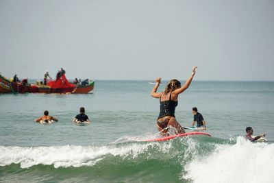 People enjoying in sea against clear sky