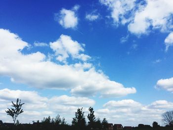 Low angle view of trees against cloudy sky