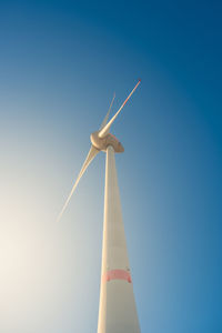 Low angle view of wind turbine against clear blue sky