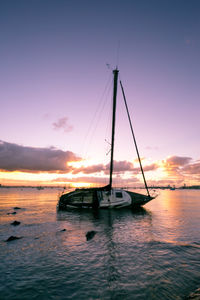 Silhouette boat sailing in sea against sky during sunset