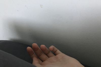 Close-up of human hand against white wall