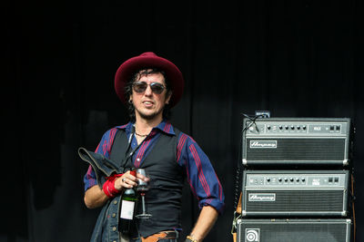 Portrait of man wearing hat standing against black background