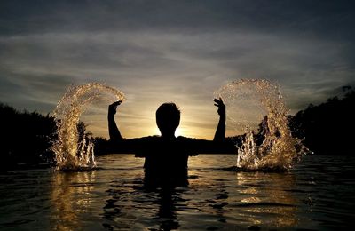 Young woman in water at sunset