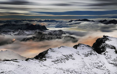 Scenic view of clouds covering snowcapped mountains