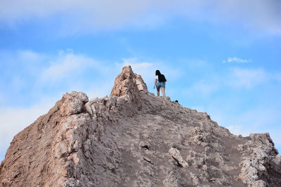 Rear view of man and woman standing on cliff against sky