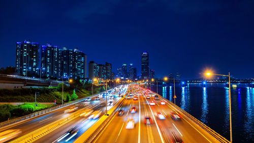 Cars on illuminated city street at night