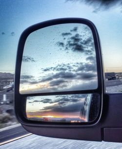 Reflection of clouds in side-view mirror