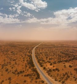 Drone aerial of a highway through the landscape of the outback with a massive dust storm on horizon