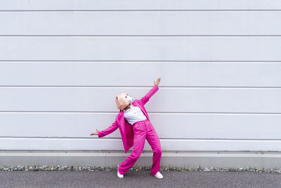 Full length of girl standing against pink wall