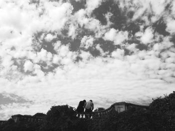 Silhouette of person standing on field against cloudy sky