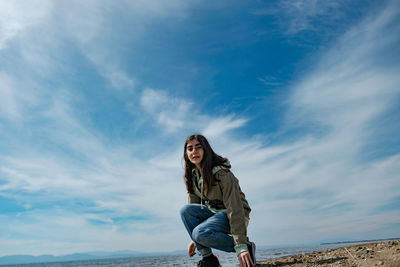 Portrait of young woman standing against sky