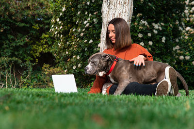 Woman with laptop and dog at park