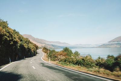 Road amidst trees and mountains against sky