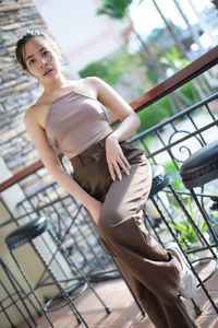 Full length of young woman sitting on railing