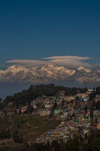 Aerial view of townscape and snowcapped mountains against blue sky