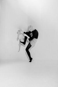 Woman holding mannequin hand while standing over white background