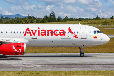 Red airplane on airport runway against sky