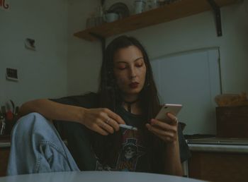 Sad woman with the cigarette and smartphone at home