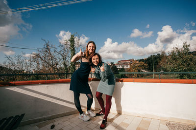 Two girls have fun time in italy. they are smiling and standing on a balcony.