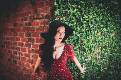 Portrait of woman standing against brick wall