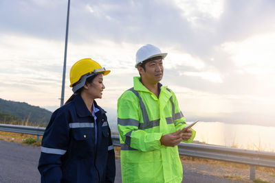 Engineers talking while standing against sky