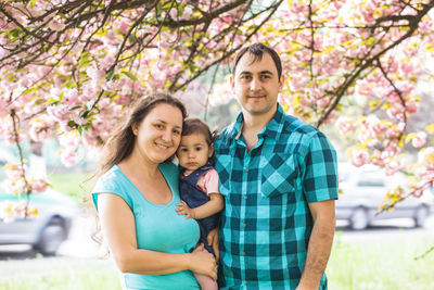 Family with daughter under pink flowers