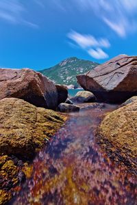 Scenic view of sea and rocks against blue sky