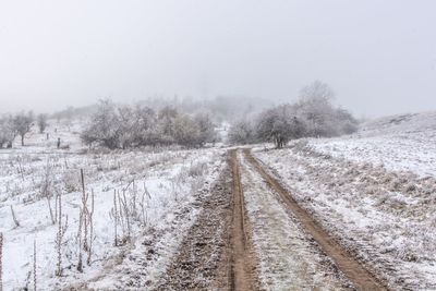 Snow covered field against sky during winter