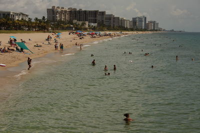 People enjoying on beach against sky