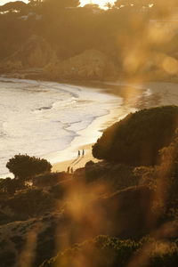 Scenic view of sea with people at the beach during sunset