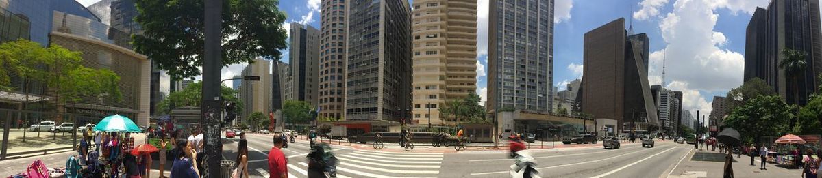 Panoramic view of people on city street amidst buildings